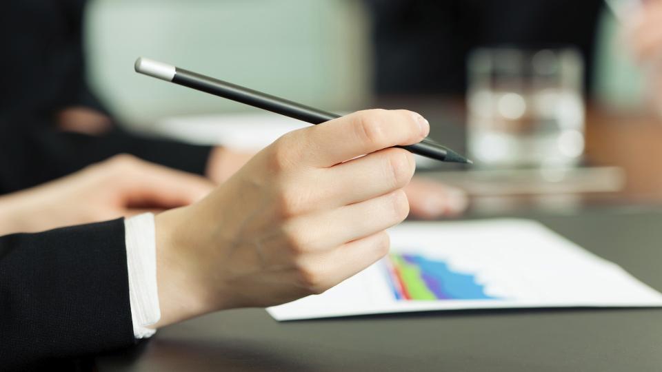 A hand clasping a pen, resting on a business document