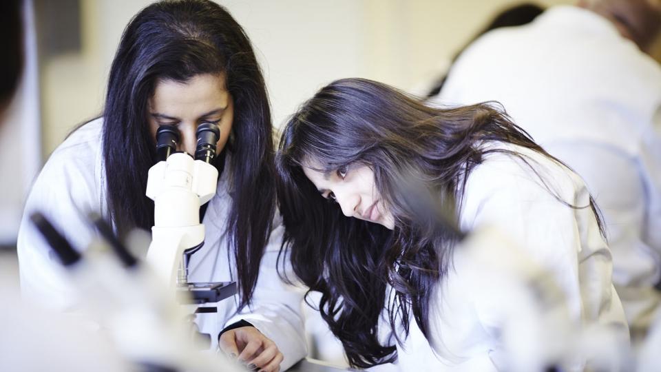 Two student forensic scientists working at a microscope