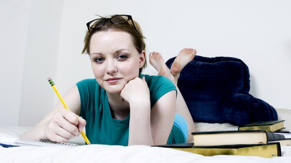 Image of student on a bed with books