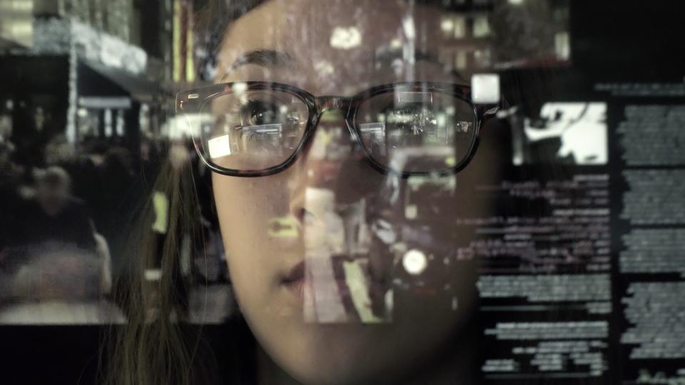 A person wearing glasses looking at a screen with data reflected