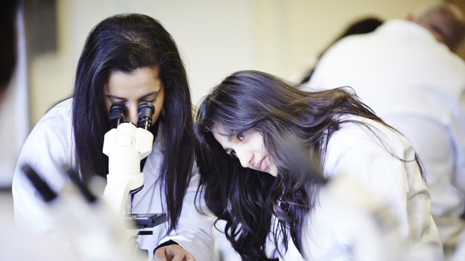Two forensic science students with a microscope
