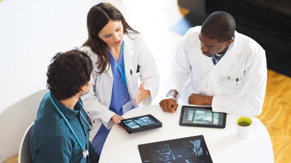 Health professionals using tablet PCs around a table