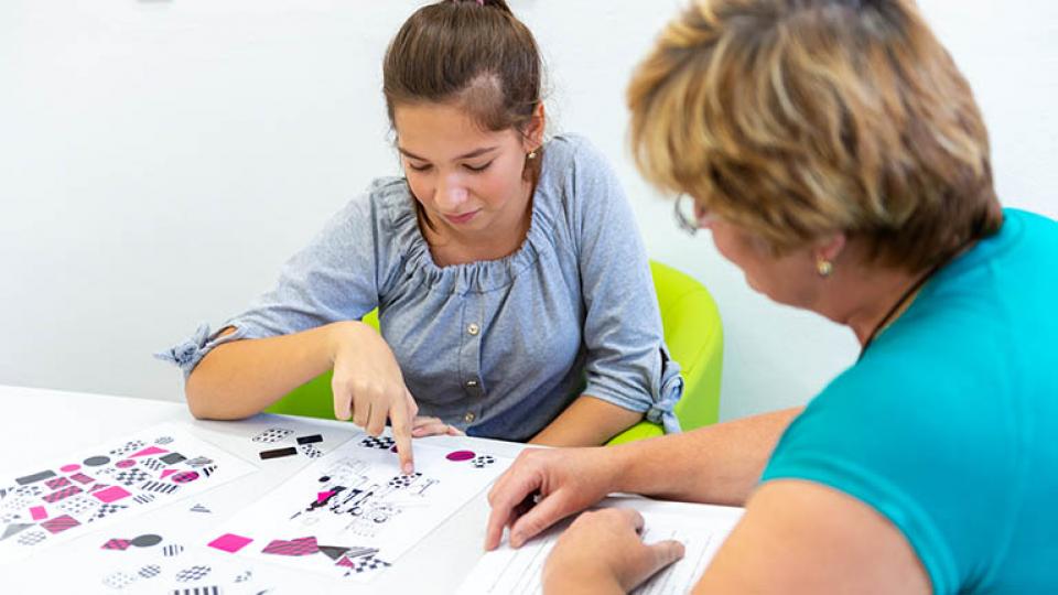 Therapist working with a teenage girl with learning difficulties to master logical tests