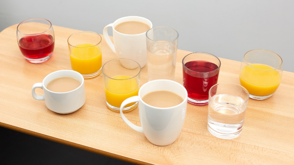 A selection of hot and cold drinks on a table, including tea, fruit juice and squash.
