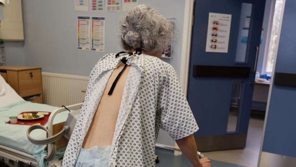 dementia patient walking with a zimmer frame in a hospital ward