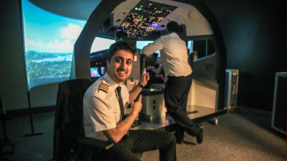 A pilot smiling and pointing to the FlightPad simulator at UWL.