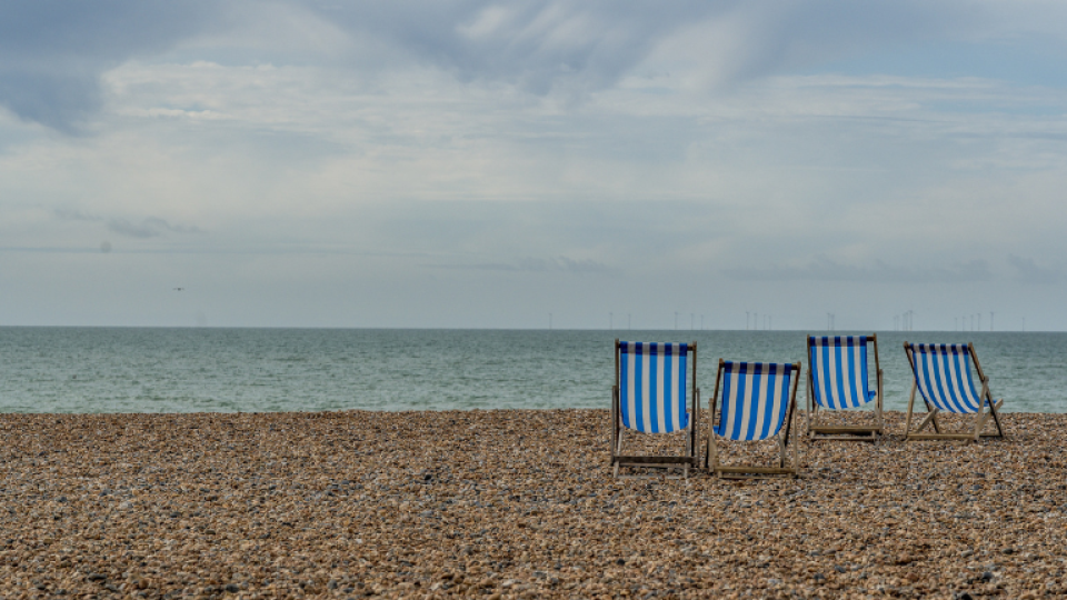 Four blue and white beach chairs sat on a beach facing a calm sea