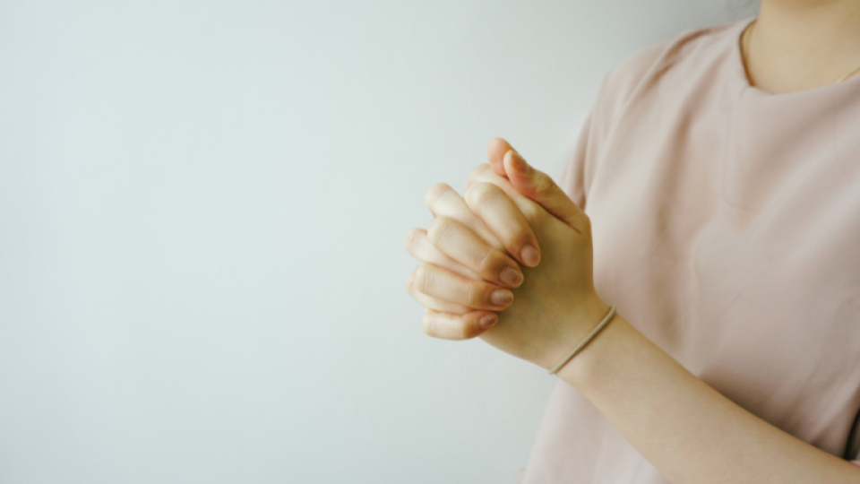 A person clasping their hands in prayer