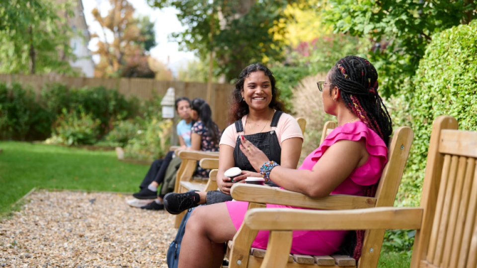 Two students socialising on a bench in the memorial garden at UWL.