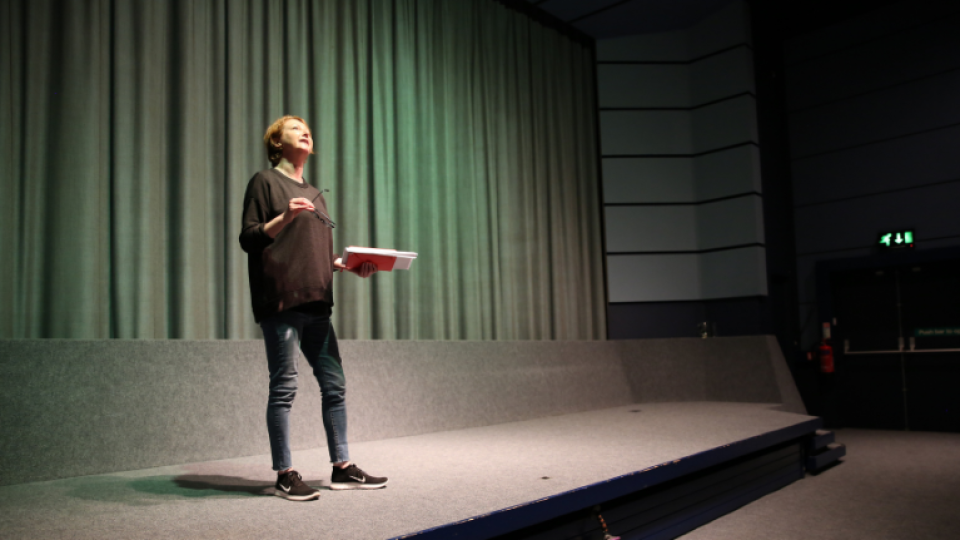 A lady on stage at a screening talking to spectators. 