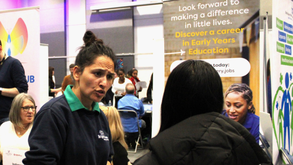 Careers advisor at a stand talking to students at a careers fair.