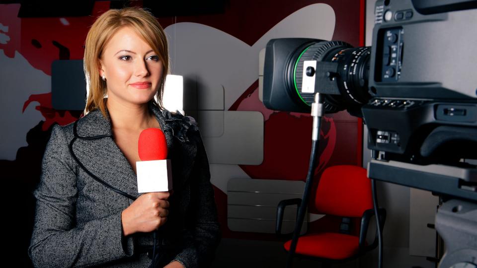A female news reporter standing in front of a camera
