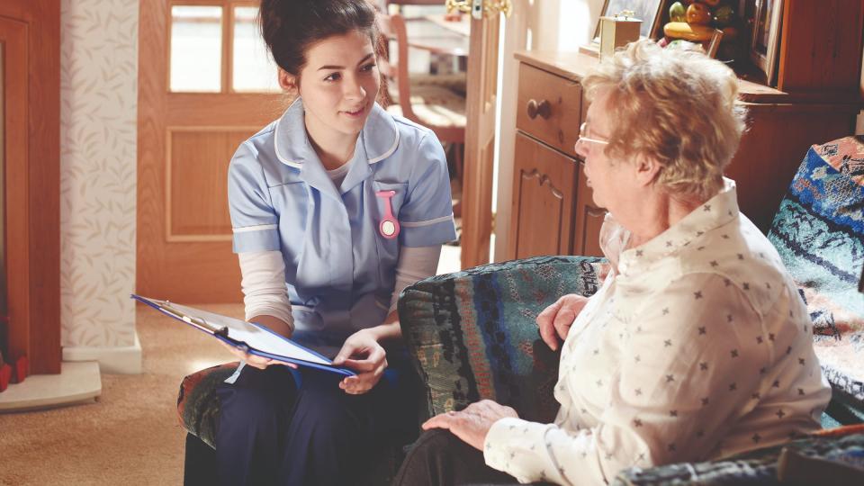 A female nurse talking to an elderly woman at home