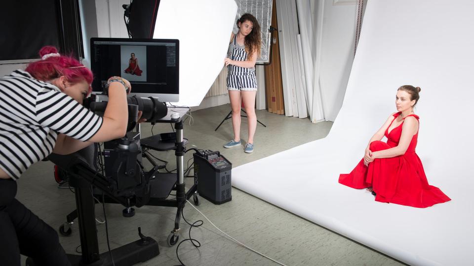 A woman in red dress being photographed in a studio