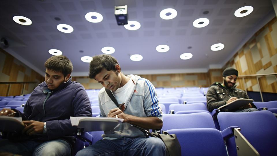 Three students studying in a lecture theatre 