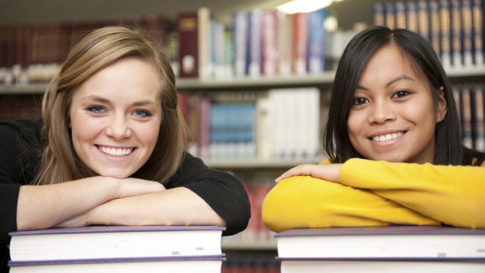 Two girls leaning on books