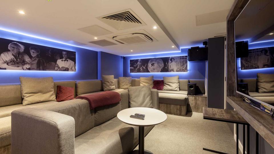 Cinema room with large screen, neon lights and sofas