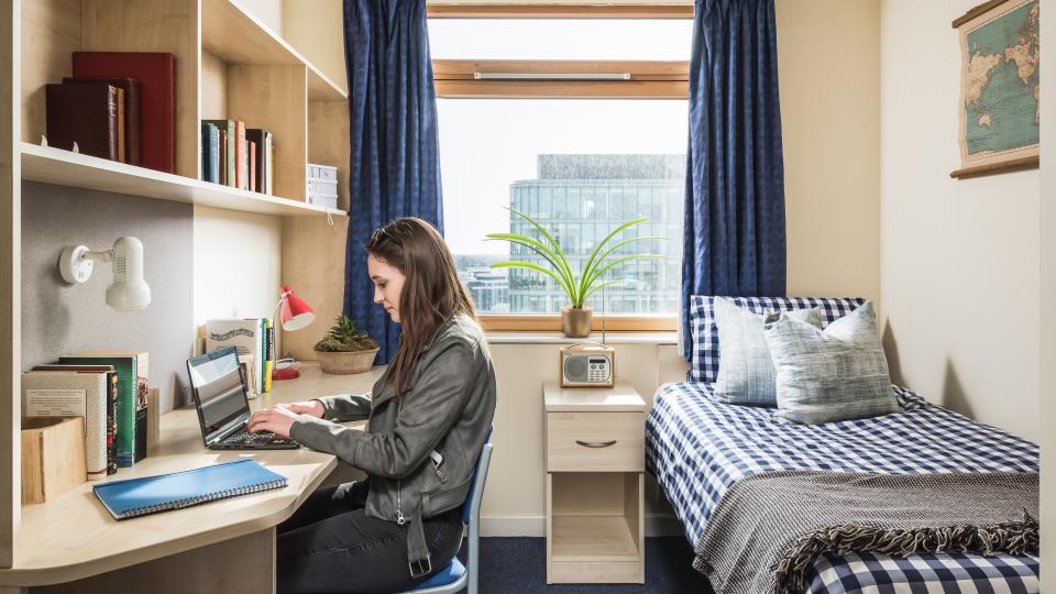 A student working on her laptop in her flat at Paragon