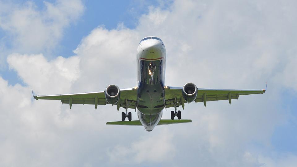 An airliner, photographed from below with a blue-sky background
