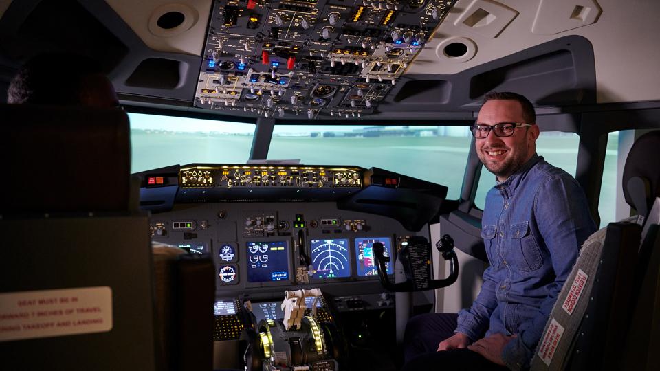 A smiling pilot using the University of West London flight simulator