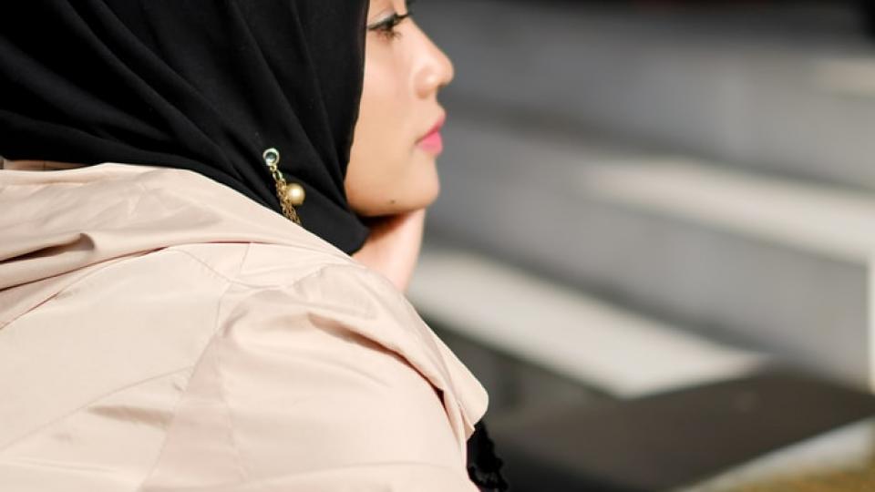 A woman wearing a black hijab and light coat