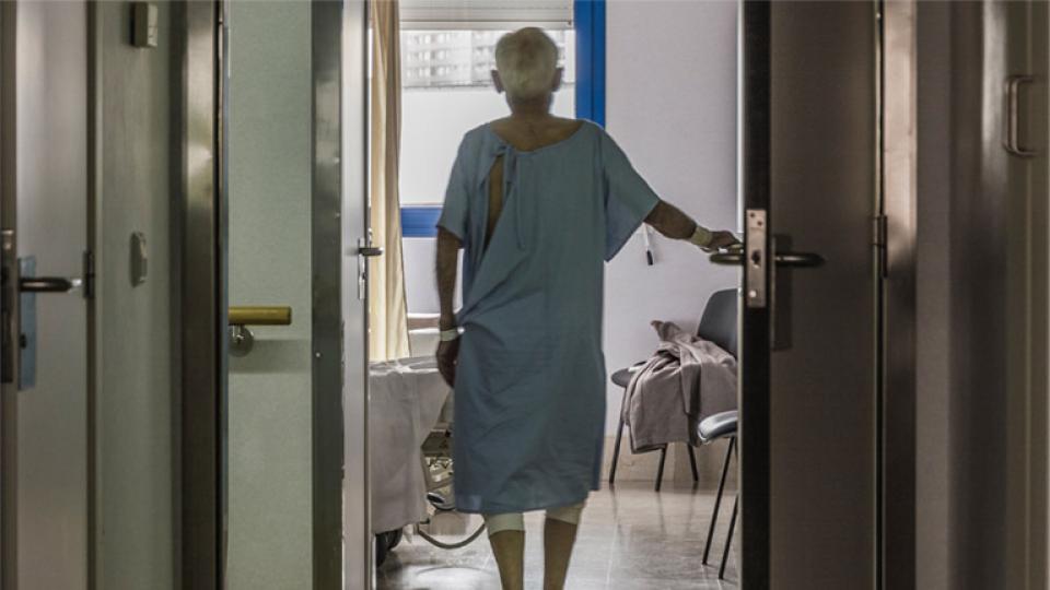 An elderly hospital patient walks unassisted through a door