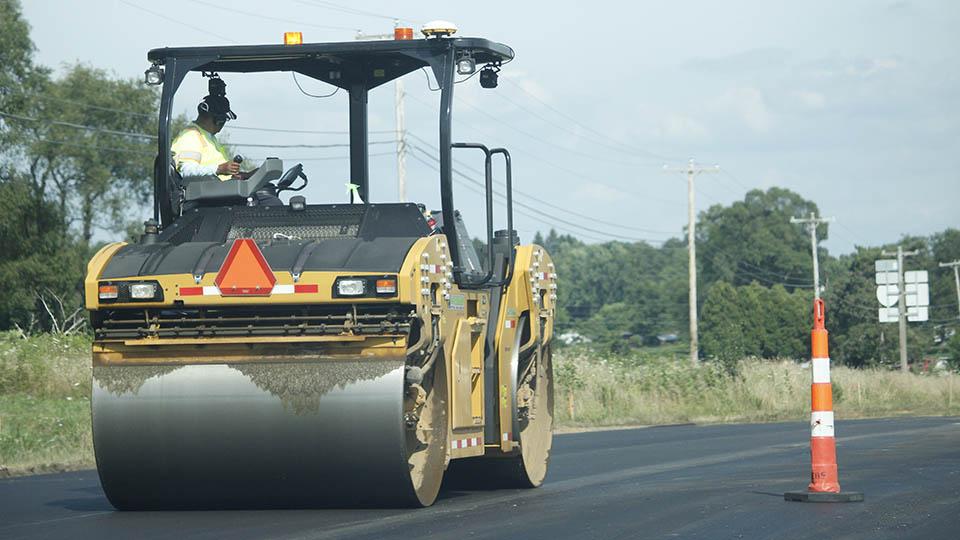 Heavy-duty road roller flattening a section of a road