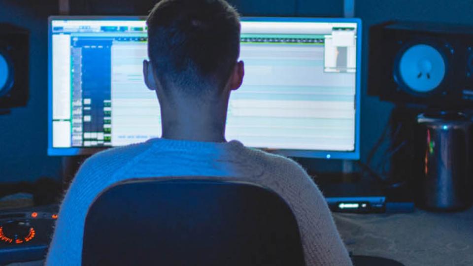 A young musician pictured using a DAW in a music studio