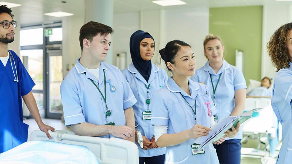 A mixed group of student nurses wearing blue uniforms