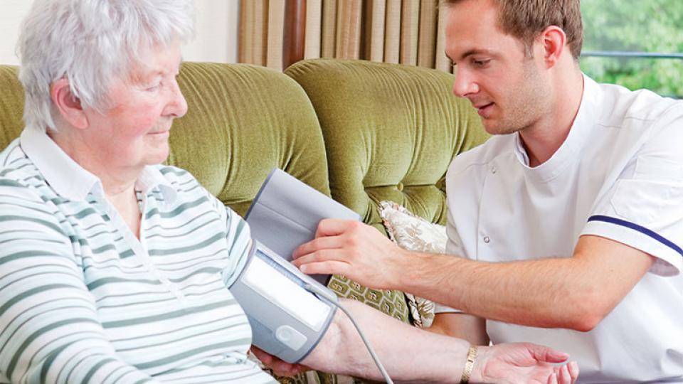 A nurse checks the blood pressure of and older patient