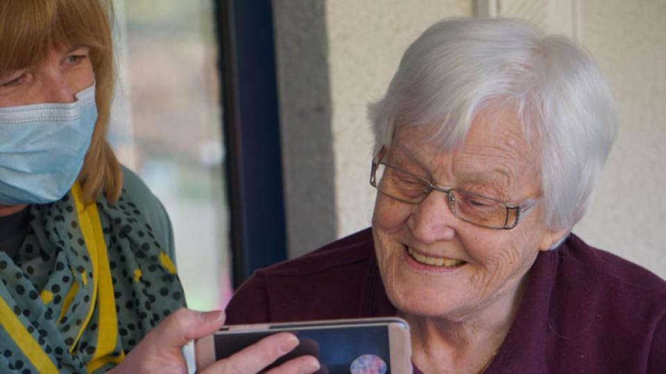 An older person looking at her carers phone