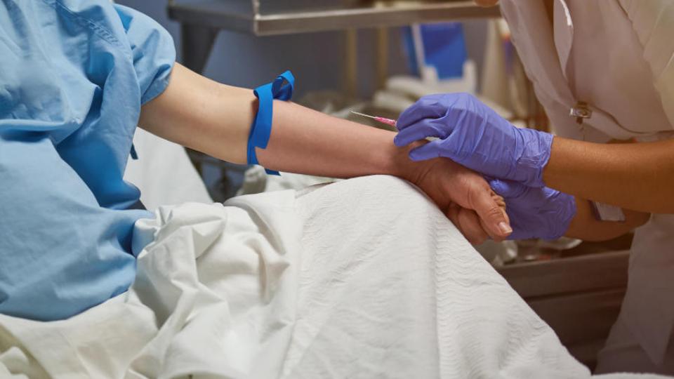 A close up view of a nurse setting up a peripheral venous catheter