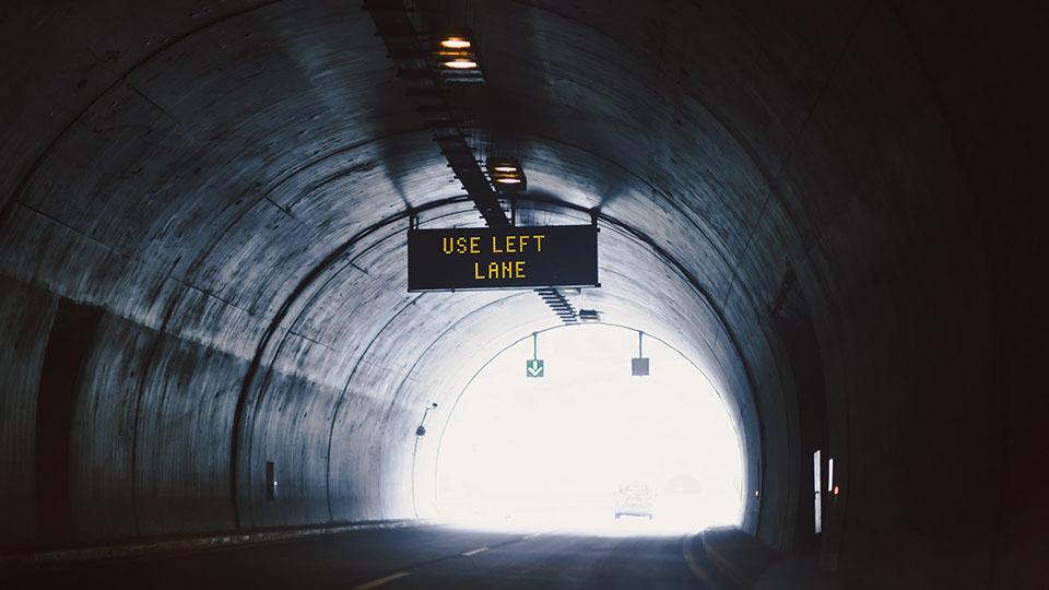 Use left lane sign hanging from the ceiling of a tunnel