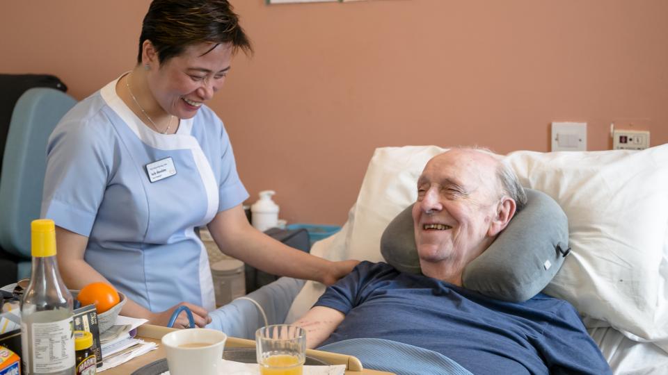 A nurse caring for a patient in a care home - they are both smiling and enjoying a moment.