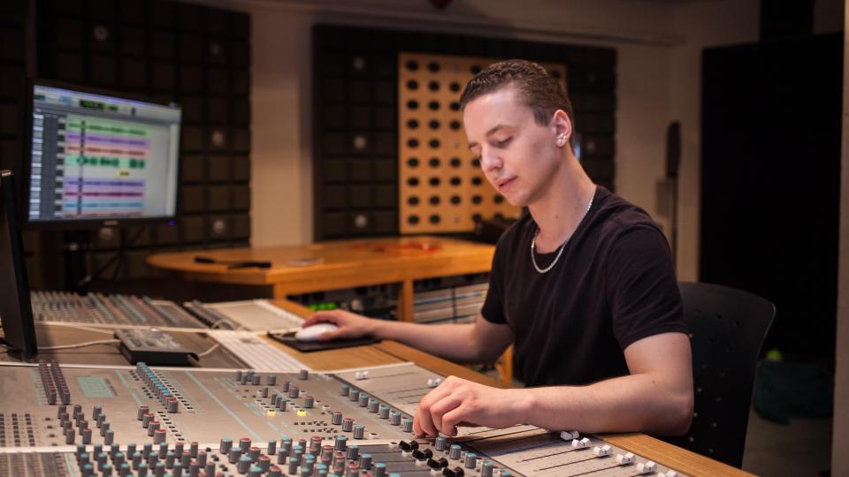 A student producer behind a mixing board