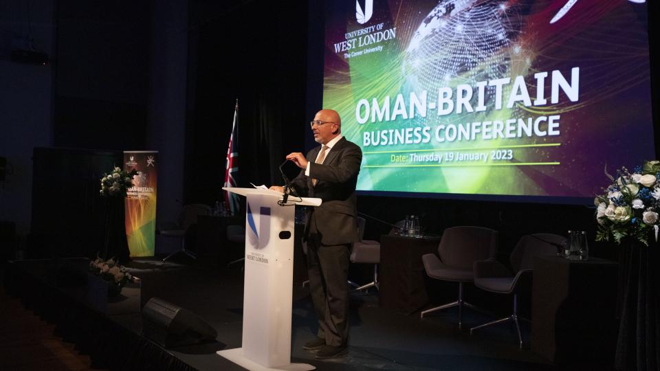 Cabinet Minister The Rt. Hon. Nadhim Zahawi MP speaking at Oman-Britain Business Conference with Oman-Britain Business Conference projected on the wall behind him.