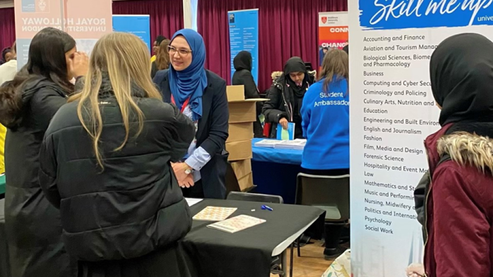 Students at the Careers and Higher Educational Fair facing a tutor at a stand.