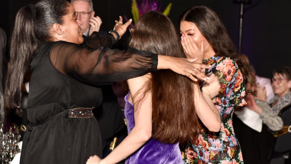 Olivia Parker-Smith, Prema Rebekah Kaur Sembi-Harding and Nekshia Alcee are in formal dress at the Zest Quest Asia Awards ceremony celebrating together whilst embracing.