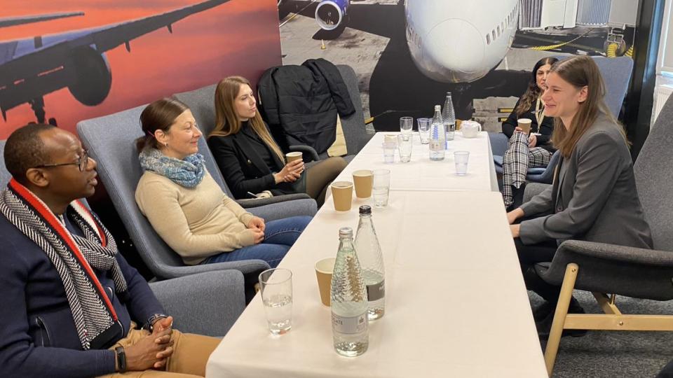 Head of Ancillary Services for Wizz Air James Goodwin, sitting with the University’s BSc (Hons) Air Transport Management (Airline and Airport Specialist) students to hold an ideas session with drinks on a table and planes printed on the walls.