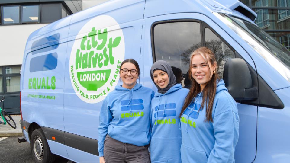 Three UWL students dressed in City Harvest branded clothes standing in front of a City Harvest branded van.