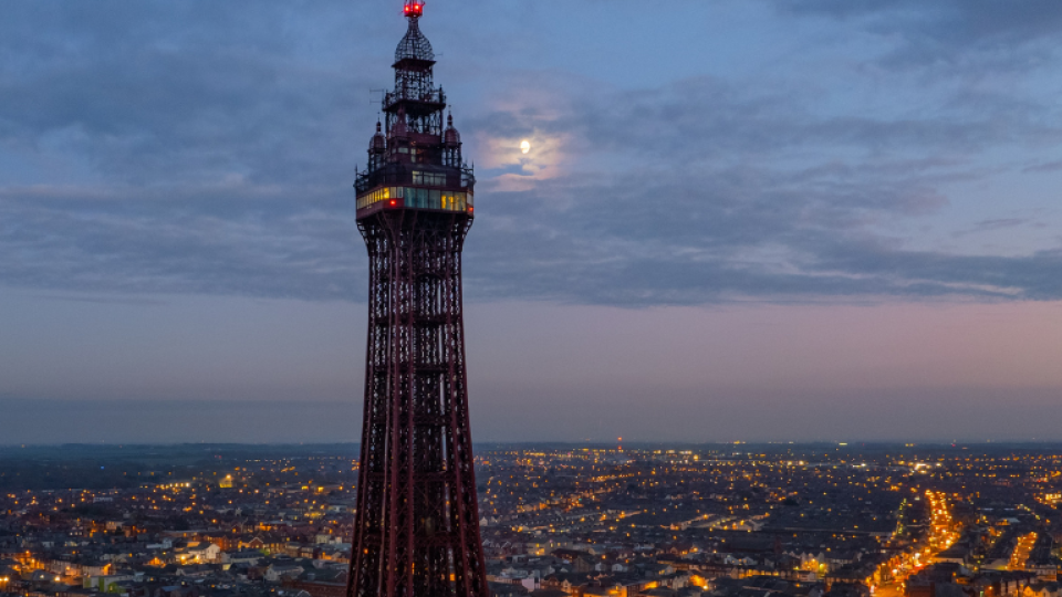 A moon shining through over Blackpool tower during twilight