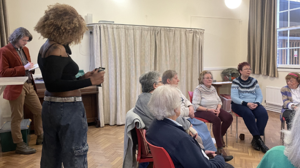 A student from the London School of Film, Media and Design filming a group of older people for Age UK
