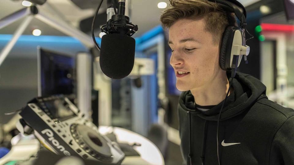 A male student with headphones talking during a radio broadcast