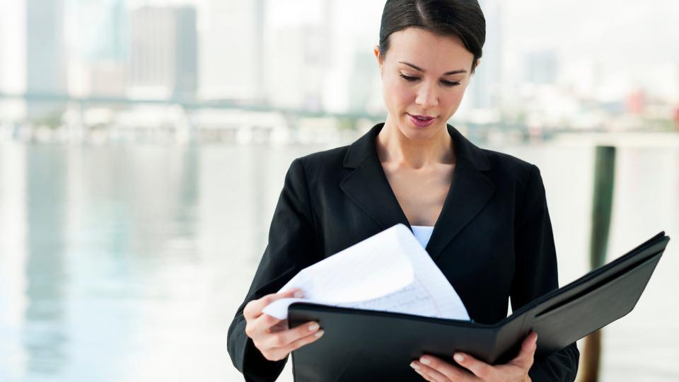 A woman in a business suit looking through a folder