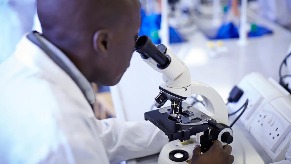 A male doctor looking into a microscope