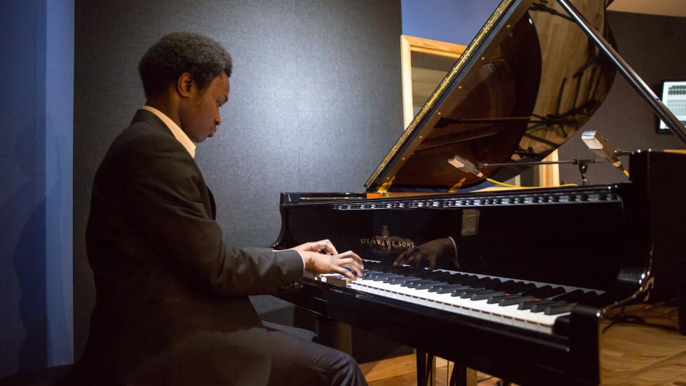 A man in a suit playing the piano in a studio