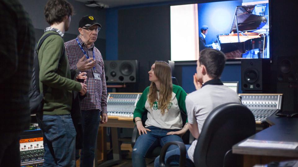 An older man talking to three people in a sound studio