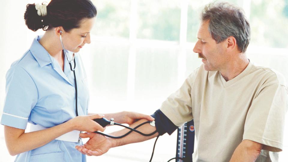 A female nurse taking a man's blood pressure