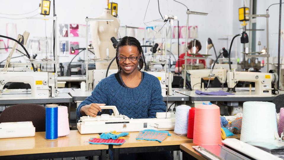 A female student working at a sewing machine in a design studio