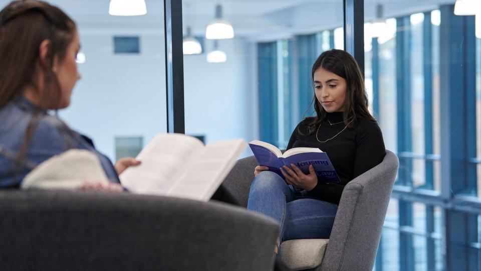 Two female students reading in the UWL library